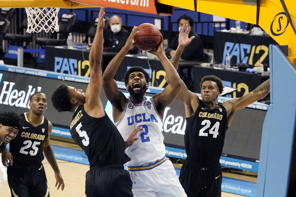 UCLA forward Cody Riley (2) shoots over Colorado guard D'Shawn Schwartz (5) and guard Eli Parquet (24) during the second half of an NCAA college basketball game Saturday, Jan. 2, 2021, in Los Angeles. (AP Photo/Marcio Jose Sanchez)