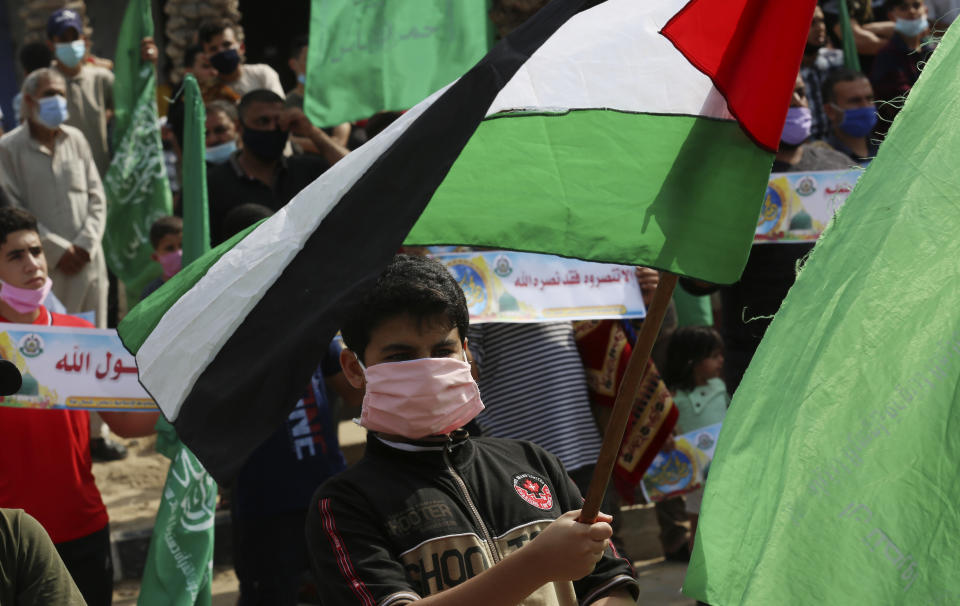 Hamas supporters wear face masks while waving the national flags during a protest against French President Emmanuel Macron and the publishing of caricatures of the Muslim Prophet Muhammad they deem blasphemous, at the main road of Jebaliya refugee camp, Gaza Strip, Friday, Oct. 30, 2020. (AP Photo/Adel Hana)