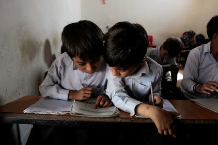 Students share a textbook during an English class at the Mashal Model school in Islamabad, Pakistan, September 26, 2017. REUTERS/Caren Firouz