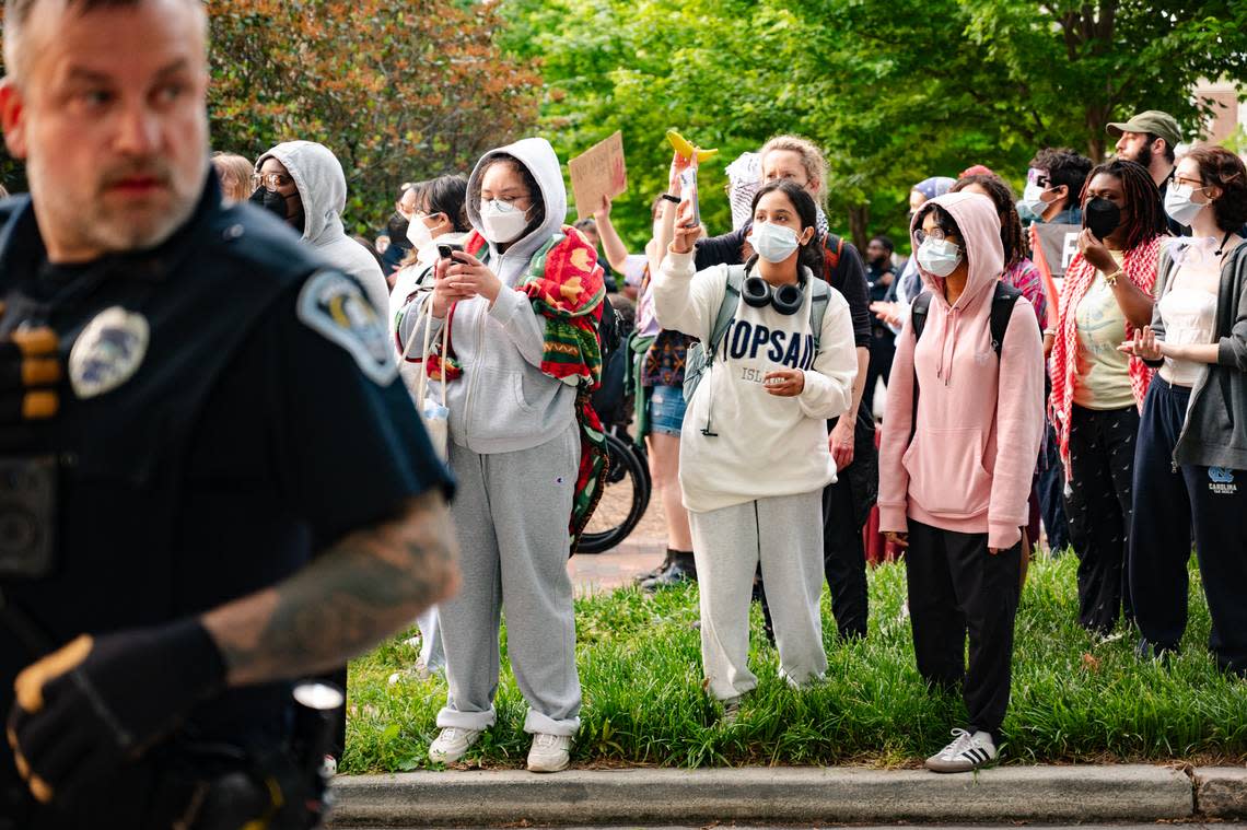 A police officer walks past protestors on E. Cameron Ave. on Tuesday, April 30. Heather Diehl