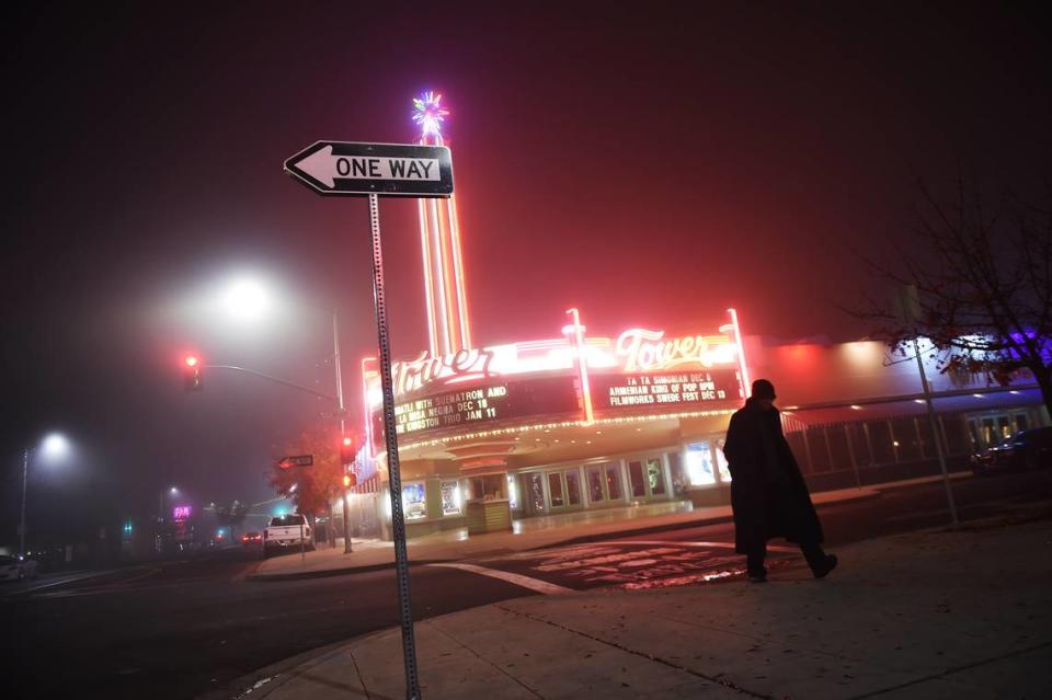 A pedestrian passes the Tower Theatre on a foggy night in Fresno in a file photo from 2019. The Painted Table is located in the same building, just to the right of the theater.