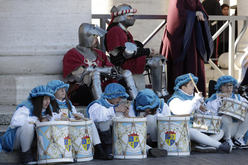 People from an historical reenactment group listen as Pope Francis recites the Angelus prayer from his studio's window overlooking St. Peter's square at the Vatican, Monday, Jan. 6, 2020. (AP Photo/Andrew Medichini)