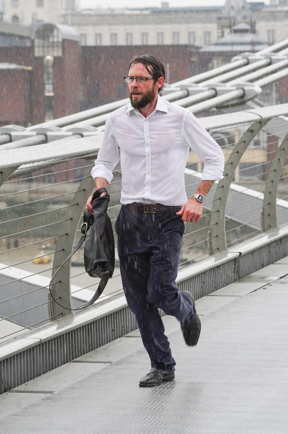 A man runs across the Millennium Bridge in the rain (PA)