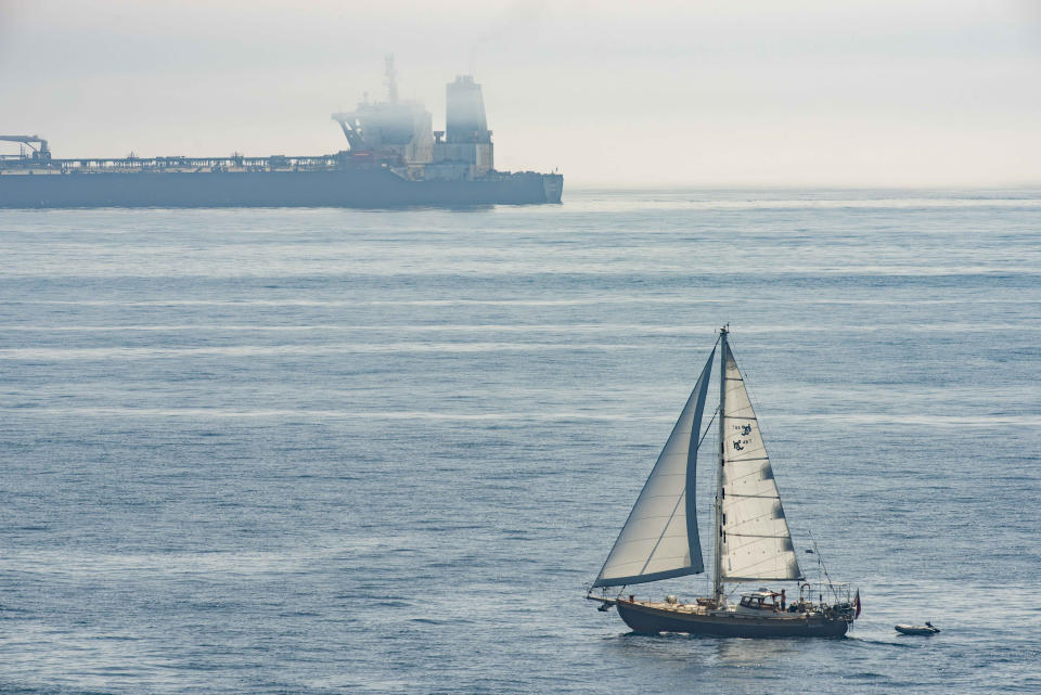 A view of the Grace 1 supertanker in the British territory of Gibraltar, Friday, Aug. 16, 2019 as a sail boat passes by. The lawyer representing the captain of the Iranian supertanker caught in a diplomatic standoff said Friday that the captain no longer wants to be in command of the ship, which is in need of repairs that could prevent its immediate departure from Gibraltar.(AP Photo/Marcos Moreno)