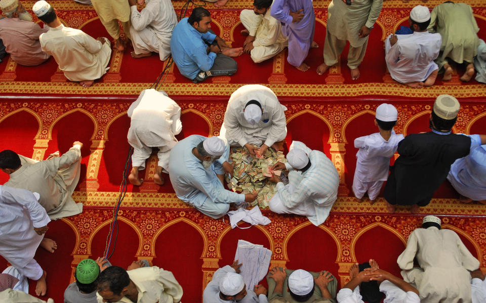 In this Friday, Aug. 17, 2012 photo, Pakistani men, center, count money they collected for worshippers to be delivered to poor families, on the last Friday of the Muslim holy fasting month of Ramadan, in a mosque in Gujranwala, Pakistan. For many years, Pakistan required all Sunni Muslims, who make up a majority of the country's population, to pay zakat to the government. That regulation changed recently, but many Pakistanis seem unaware and continue to pull their money out of the bank to elude the state. (AP Photo/Aftab Rizvi)