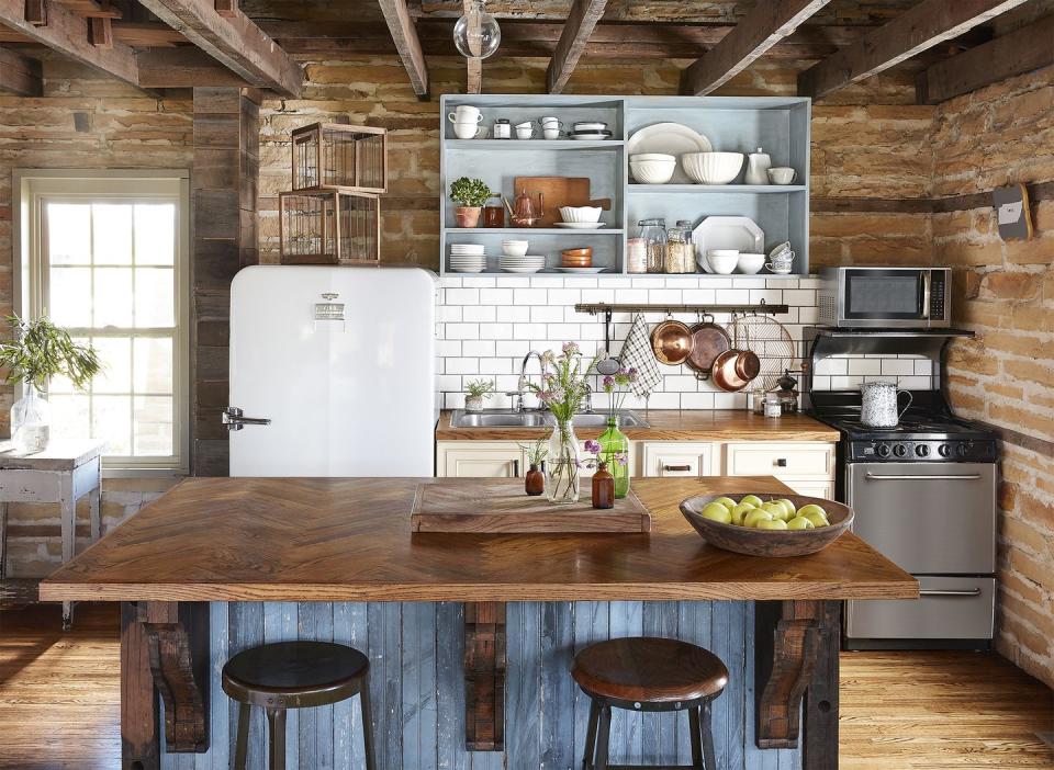 a farmhouse kitchen that has bare walls and reclaimed blue washed wood makes up the kitchen island