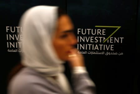 FILE PHOTO: A woman walks past a sign during the Future Investment Initiative conference in Riyadh