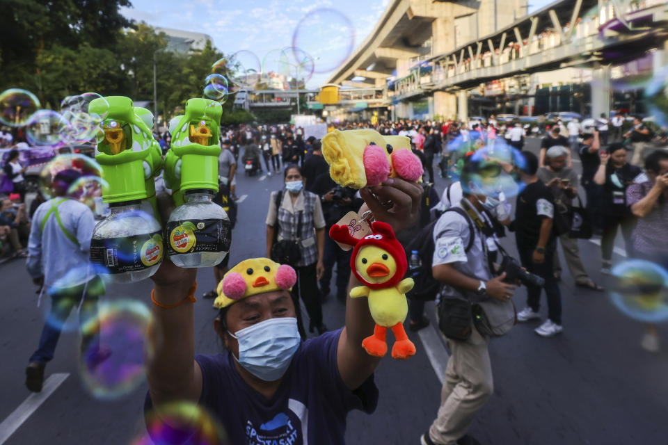 CORRECTS PHOTOGRAPHER'S NAME - A man holds up bubble blowers and merchandise designed as yellow ducks, which have become good-humored symbols of resistance during anti-government rallies, Friday, Nov. 27, 2020 in Bangkok, Thailand. Pro-democracy demonstrators are continuing their protests calling for the government to step down and reforms to the constitution and the monarchy, despite legal charges being filed against them and the possibility of violence from their opponents or a military crackdown. (AP Photo/Wason Wanichakorn)