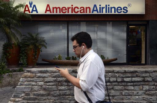 Un hombre camina por enfrente de una oficina de venta de boletos de la aerolínea estadounidense American Airlines, en Caracas, Venezuela, el 17 de junio de 2014. La aerolínea reducirá a partir de julio la frecuencia de sus vuelos a Venezuela, tras no llegar a un acuerdo con el gobierno para cobrar una millonaria deuda. (AFP | Leo Ramirez )