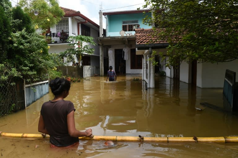 Sri Lankan residents make their way through floodwaters in Kaduwela. Emergency teams are rushing to distribute aid to half a million displaced after the island's worst flooding in more than a decade claimed 126 lives and left scores more missing