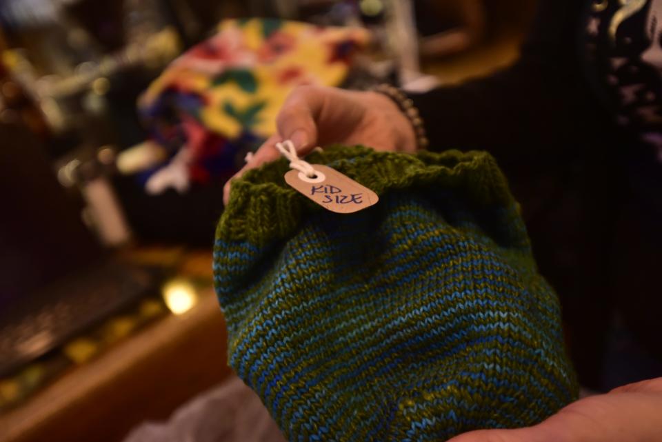 Co-owner Jody Parmann holds a kids size winter hat as part of their Cozy Crates drive designated to provide free winter clothing for anyone in need at The Raven Cafe at 932 Military St., in downtown Port Huron on Tuesday, Nov. 29. 2022. Brian’s Drive Thru Eggairy and the St. Clair County Library System are also offering free winter clothing in various ways largely donated by the community, to make sure people don’t go cold this winter.