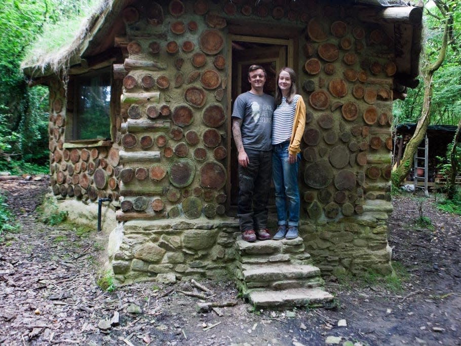 man and woman stand in front of their hobbit house in south wales