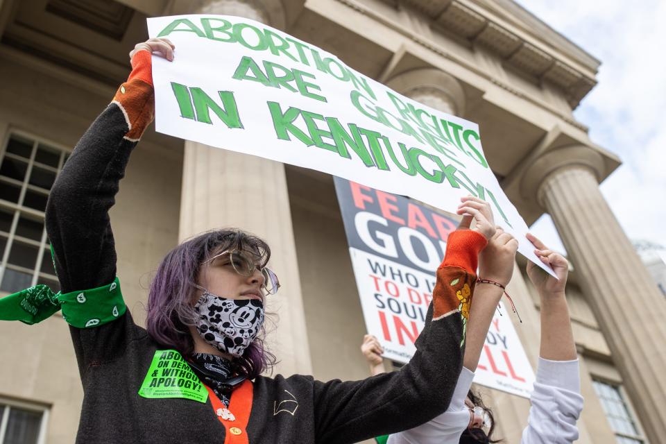 Protesters hold a sign outside Louisville Metro Hall on April 21, 2022, where supporters and opponents of Kentucky's new abortion law gathered. A federal judge blocked the law while the protest was underway.