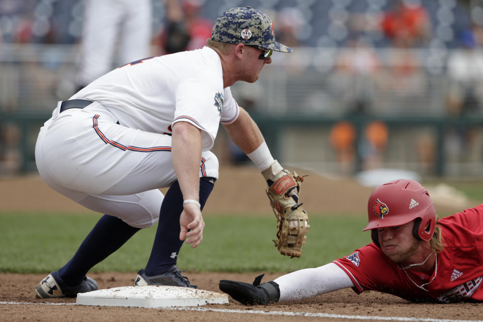 Louisville's Adam Elliott, right, slides back to first base on a pickoff attempt by Auburn first baseman Rankin Woley in the seventh inning of an NCAA College World Series baseball game in Omaha, Neb., Wednesday, June 19, 2019. (AP Photo/Nati Harnik)