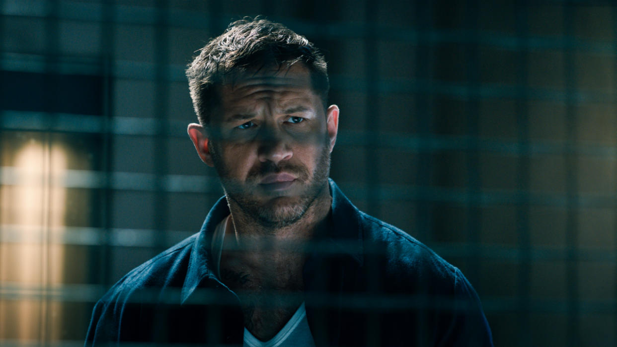  Tom Hardy stands in front of a prison cell in Venom Let There Be Carnage. 