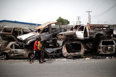 Two men walk past burnt cars piled in a street of Port-au-Prince, Haiti, July 12, 2018. REUTERS/Andres Martinez Casares