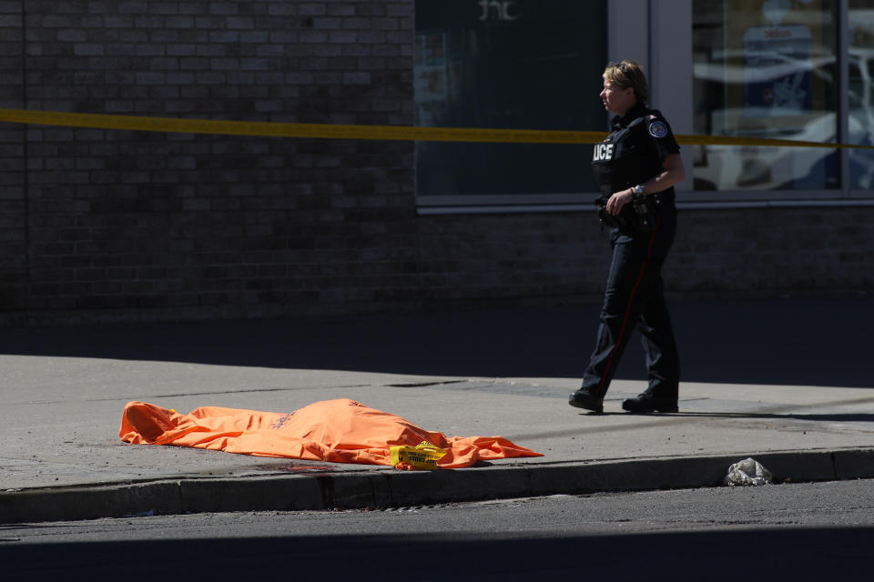 A member of the police stands next to an unidentified body near the crime scene.&nbsp;