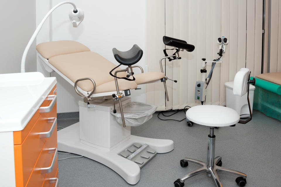 A gynecological cabinet with chair and other medical equipment in a clinic.