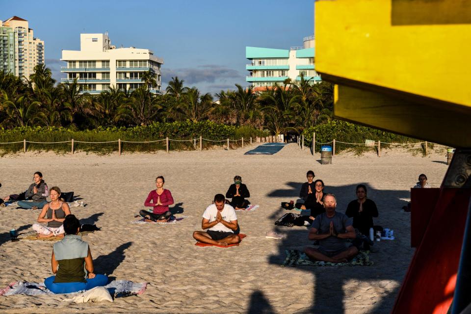 A group of people participate in a yoga session taught by Radha Silva on the beach in Miami Beach, Florida, on March 23, 2021.