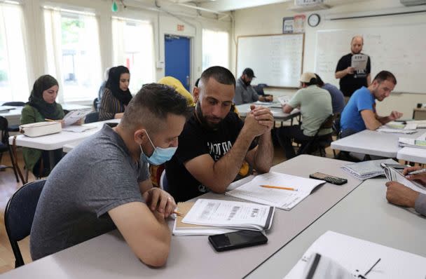 PHOTO: Najib Mohammadi ,center, talks with a classmate during a vocabulary lesson at the Highlands Adult Charter School where he attends classes in Sacramento, Calif., June 7, 2022. (Brittany Hosea-Small/Reuters)