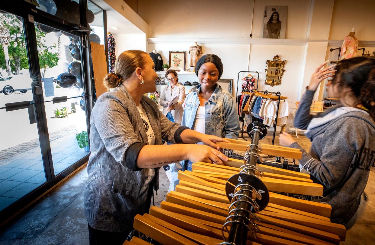 Lakeland store manger Hannah Simmons helps Sierra Wilson and Destiney Rosales pickout clothing during an event at at Top Buttons Boutique in Winter Haven. Top Buttons hosted a day of service for at-risk girls by offering clothes and life skills. ERNST PETERS/THE LEDGER