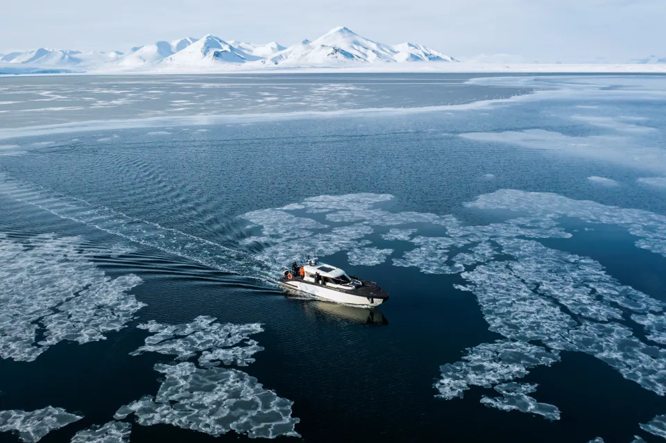 A hybrid touristic boat threads its way through clumps of sea ice.