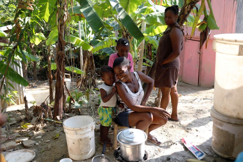 Frena Remorin, 30, (seated) cooks bananas in the improvised kitchen in the yard of her house in Jean-Rabel