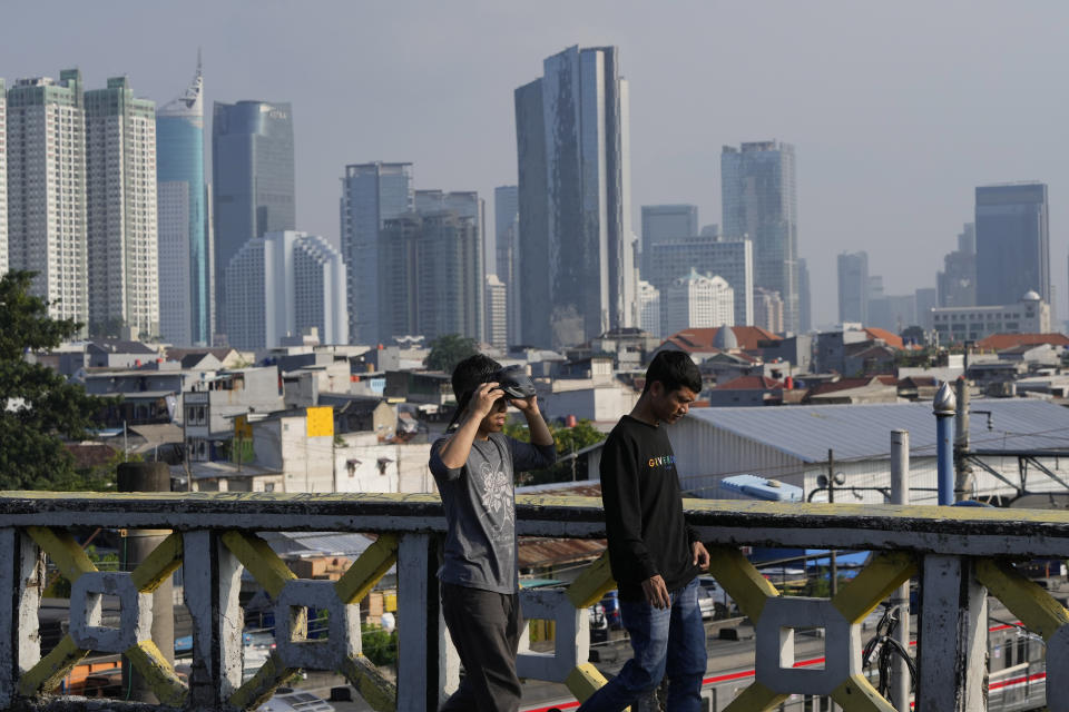 Men walk, with the city skyline in the background, in Jakarta, Indonesia, Monday, Feb. 12, 2024. When millions of Indonesians pick their new president in one of the world's biggest elections on Feb. 14, the United States and China would be closely watching who will next lead a key Asian battleground coveted for its huge market, nickel and voice. (AP Photo/Achmad Ibrahim)