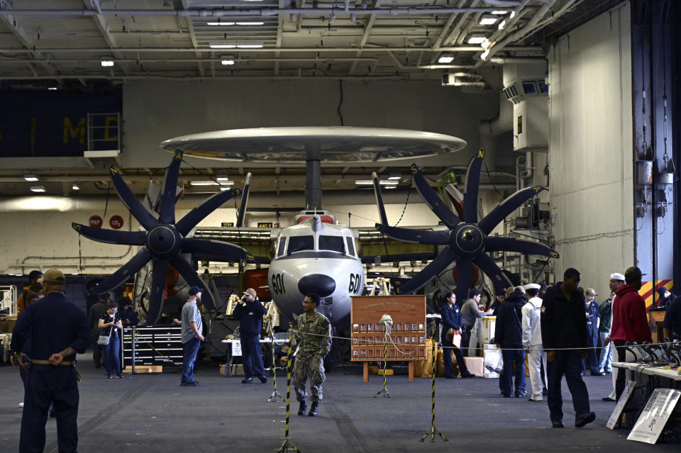 Crew members walk by aircraft in the hanger of the Theodore Roosevelt (CVN 71), a nuclear-powered aircraft carrier, anchored in Busan Naval Base in Busan, South Korea Saturday, June 22, 2024. (Song Kyung-Seok/Pool Photo via AP)