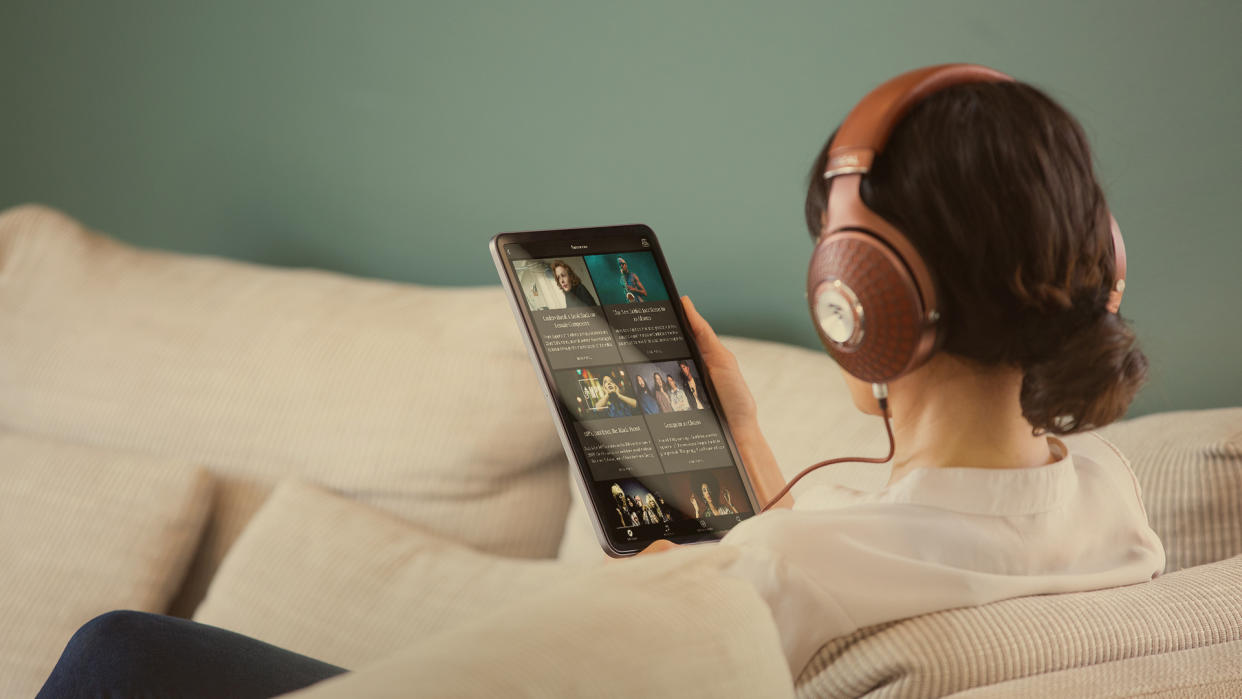  A woman holding a tablet, streaming Qobuz music with Focal Stellia over-ear headphones. 