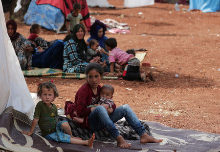 A displaced Syrian girl from the al-Ahmed family holds a baby as she sits on a mat laid out on the floor in an olive grove in the town of Atmeh, Idlib province, Syria, May 16, 2019. REUTERS/Khalil Ashawi