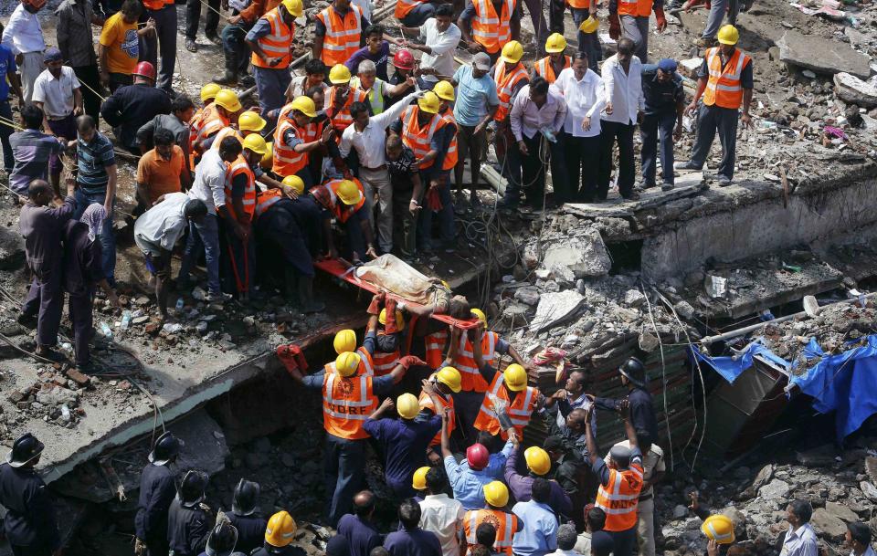 Rescue workers use a stretcher to carry a woman who was rescued from the rubble at the site of a collapsed residential building in Mumbai