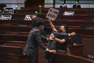 Pan-democratic legislator Chan Chi-chuen holding a placard reading "A murderous regime stinks for ten thousand years" scuffles with security guards at the main chamber of the Legislative Council dropping a pot of a pungent liquid in the chamber in Hong Kong, Thursday, June 4, 2020. A Hong Kong legislative debate was suspended Thursday afternoon ahead of an expected vote on a contentious national anthem bill after pro-democracy lawmakers staged a protest.(AP Photo/Chan Cheuk Fai/Initium)