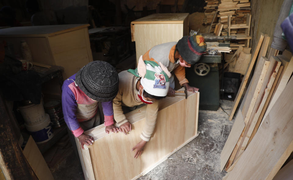 Three of the Delgado children, from right, Yuri, 11, Wendi, 9, and Alison, 8, make a drawer in the family carpentry workshop in El Alto, Bolivia, Wednesday, Sept. 2, 2020. In a country where informal employment makes up 70% of the economy, the closure of schools because of the new coronavirus pandemic puts more kids like the Delgados to work. (AP Photo/Juan Karita)