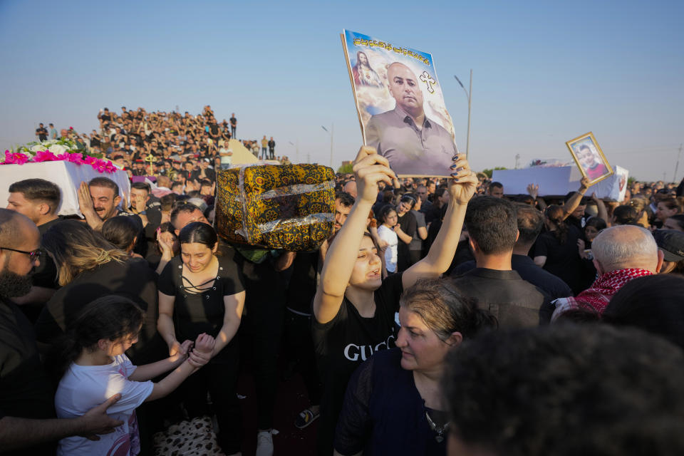 Friends and relatives attend the funeral of people who died in a fire during a wedding ceremony in Hamdaniya, Iraq, Wednesday, Oct. 27, 2023. A fire that raced through a hall hosting a Christian wedding in northern Iraq has killed around 100 people and injured 150 others, and authorities warn the death toll could rise. (AP Photo/Hadi Mizban