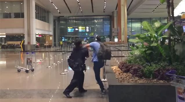 The man attempts to push the police officers away. Photo: Youtube / Ben Bonifant