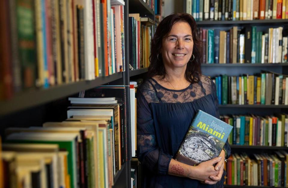 Traci Ardren, an anthropologist and archaeologist at the University of Miami, poses with a book on Florida archaeology in her campus office.