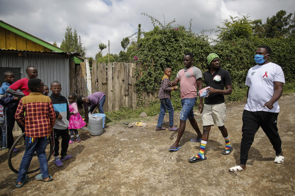 In this photo taken Thursday, June 11, 2020, gay Ugandan refugees Martin Okello, third from right, Chris Wasswa, second from right, and Kasaali Brian, right, return from shopping for food in Nairobi, Kenya. Members of the LGBT community in East Africa face discrimination that has forced many to flee their home countries for Kenya, which has become a haven for them. (AP Photo/Brian Inganga)