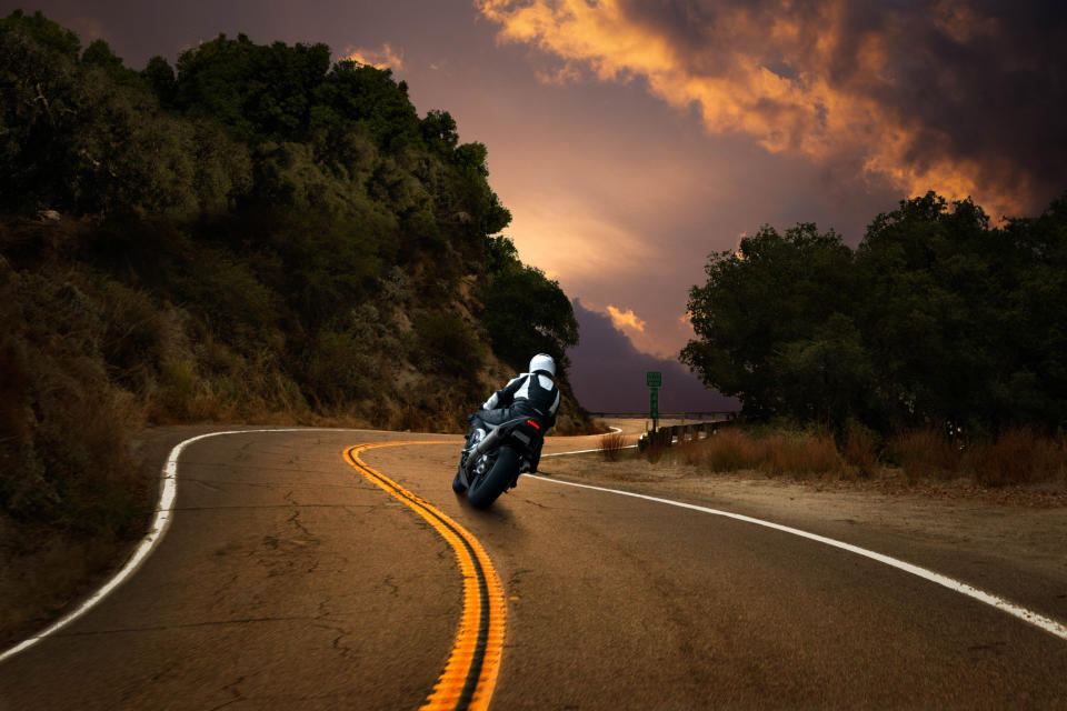 A person riding a motorcycle on a winding two-lane road