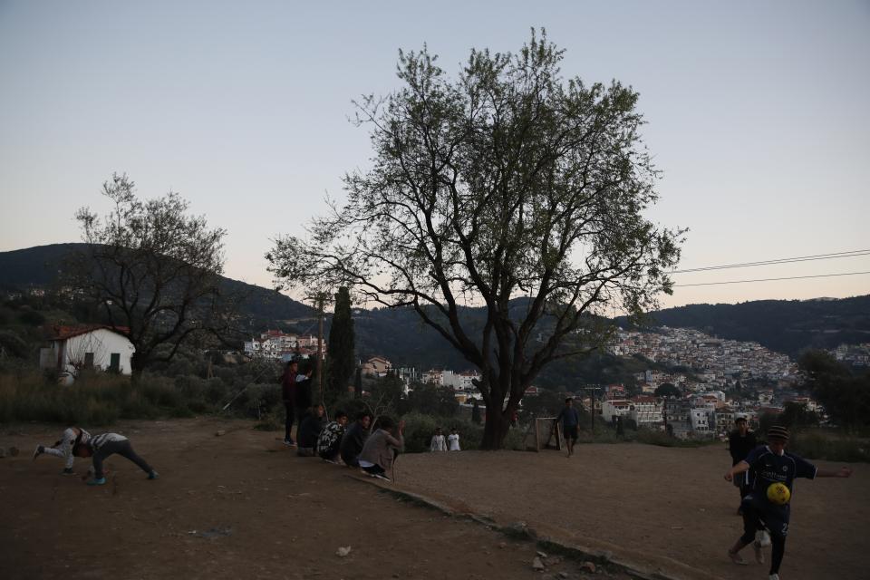 Migrants play soccer outside the perimeter of the overcrowded refugee camp at the port of Vathy on the eastern Aegean island of Samos, Greece, Tuesday, Feb. 23, 2021. On a hill above a small island village, the sparkling blue of the Aegean just visible through the pine trees, lies a boy’s grave. His first ever boat ride was to be his last - the sea claimed him before his sixth birthday. His 25-year-old father, like so many before him, had hoped for a better life in Europe, far from the violence of his native Afghanistan. But his dreams were dashed on the rocks of Samos, a picturesque Greek island almost touching the Turkish coast. Still devastated from losing his only child, the father has now found himself charged with a felony count of child endangerment. (AP Photo/Thanassis Stavrakis)