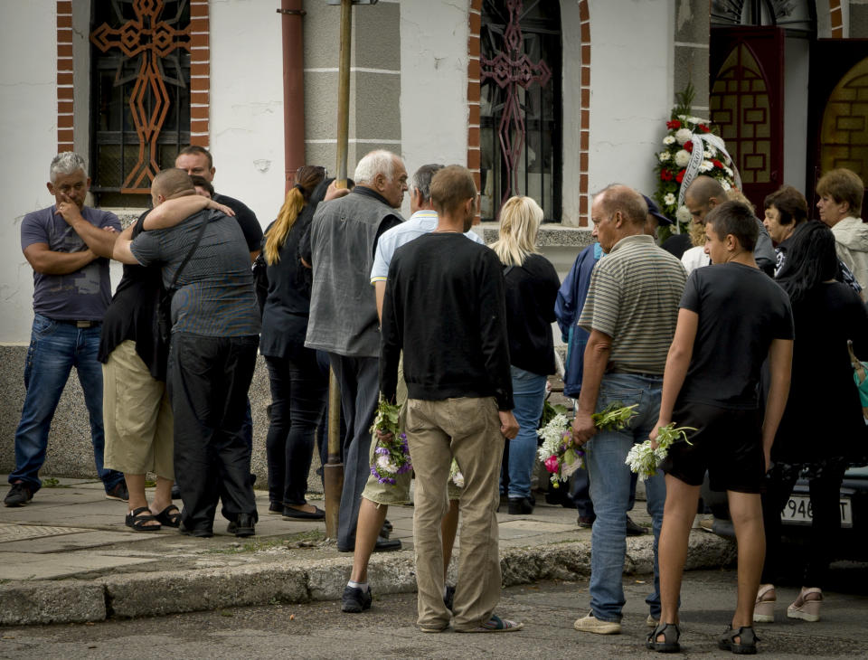 Bulgarians take part in a funeral for victims of a bus crash, in Svetovrachene, Bulgaria, Tuesday, Aug. 28, 2018. A Bulgarian village just outside the capital has held funeral services for 15 of its residents who died in a bus crash over the weekend. Many of the 2,000 residents of Svetovrachene who came to pay final respects on Tuesday were related to the victims of the accident, which killed 17 people when a bus full of religious pilgrims overturned and fell off a highway about 50 kilometers (30 miles) north of Sofia. (AP Photo/Filip Dvorski)