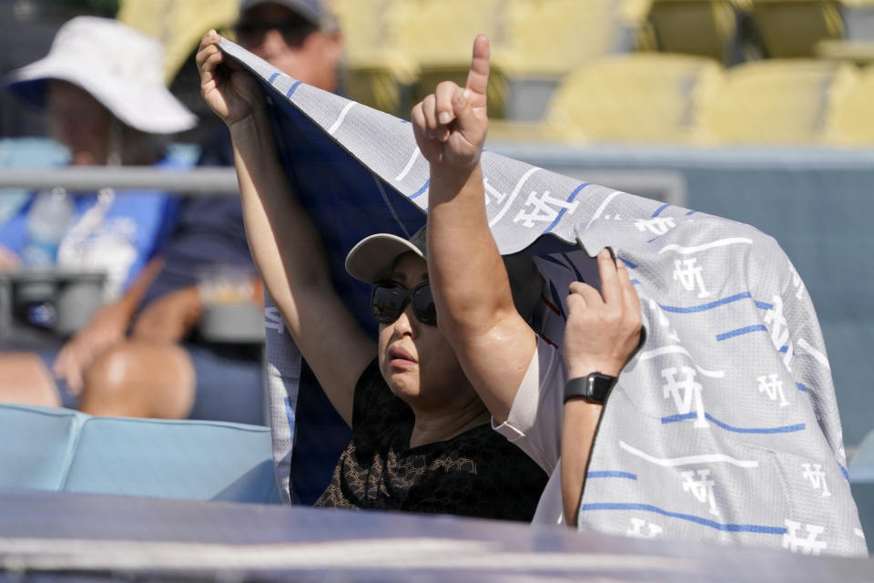 Fans shield themselves from the Sun prior to a baseball game between the Los Angeles Dodgers and the San Diego Padres Sunday, Sept. 4, 2022, in Los Angeles. (AP Photo/Mark J. Terrill)