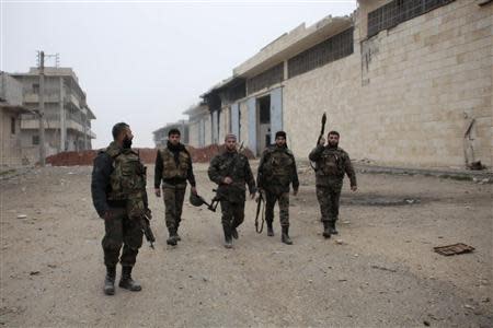 Syrian army soldiers loyal to Syria's President Bashar al-Assad walk with their weapons in the Aleppo town of Naqaren, after claiming to have regained control of the town, January 14, 2014. REUTERS/George Ourfalian