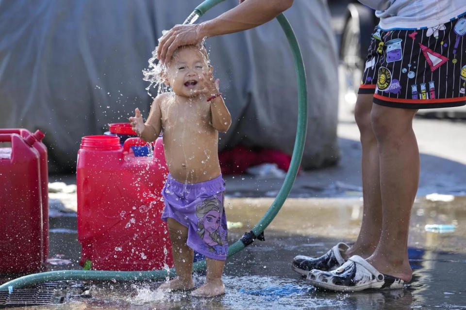 <strong>菲律賓馬尼拉高溫不斷，孩童街頭澆水降溫。（圖／美聯社）</strong>