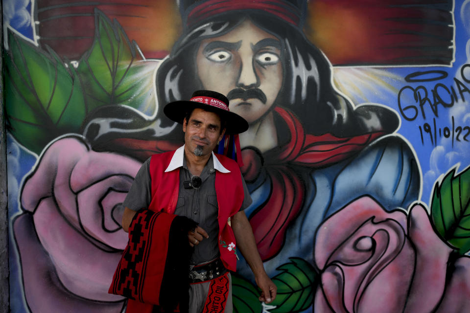 Carlos Maiana poses for a picture in front of a mural depicting folk Saint "Gauchito" Gil during his visit to his sanctuary in Mercedes Corrientes, Argentina, Saturday, Jan. 6, 2024. (AP Photo/Natacha Pisarenko)