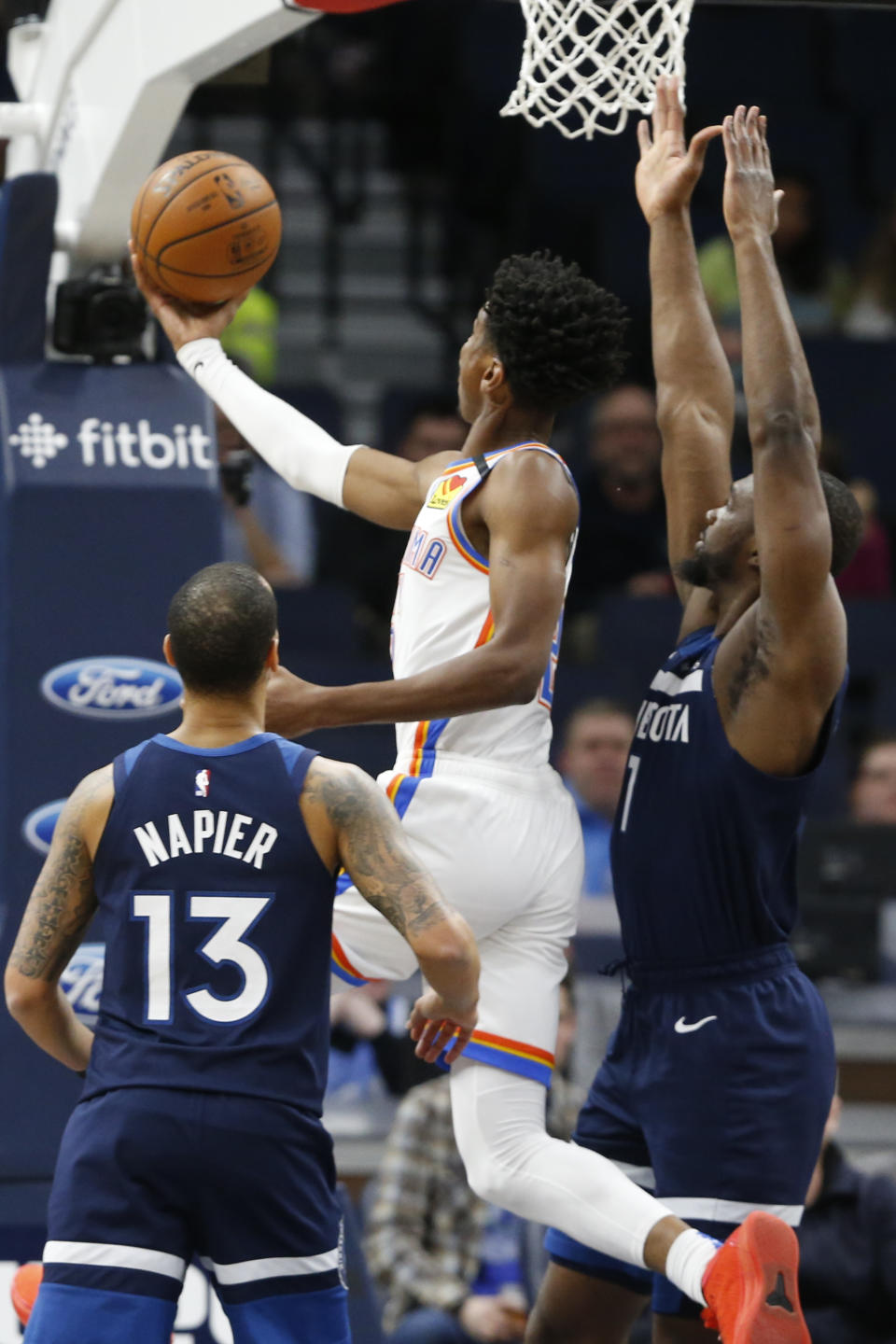 Oklahoma City Thunder's Shai Gilgeous-Alexander, center, of Canada, lays up a shot as Shabazz Napier, left, and Minnesota Timberwolves' Noah Vonleh defend in the first half of an NBA basketball game Monday, Jan. 13, 2020, in Minneapolis. (AP Photo/Jim Mone)