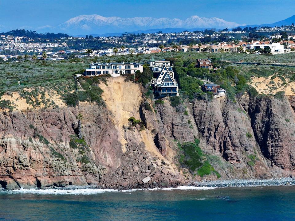 Cliff-top houses along Scenic Drive sit close to a landslide in Dana Point, Calif., on Tuesday, Feb. 13, 2024. The three homes affected by the recent deluge of rain across Orange County are being monitored but don't appear to be in imminent danger, county officials said.