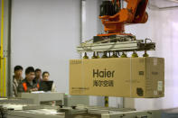 In this Friday, Feb. 24, 2017 photo, factory workers watch as a machine uses suction to lift a box containing an air conditioner at a Haier factory in Jiaozhou near Qingdao in eastern China's Shandong Province. Zhang Ruimin built Haier from a failing refrigerator factory in the 1980s into the biggest maker of major appliances. Now, he is trying to transform a traditional manufacturer with 60,000 employees in 25 countries into a nimble, Internet Age seller of consumer goods and services from web-linked washing machines to food delivery. (AP Photo/Mark Schiefelbein)