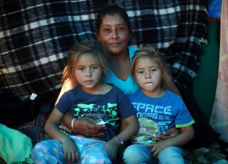Maria Meza, a 40-year-old migrant woman from Honduras, part of a caravan of thousands from Central America trying to reach the United States, sits with her five-year-old twin daughters Cheili Mejia Meza and Saira Mejia Meza inside their tent in a temporary shelter in Tijuana, Mexico, November 26, 2018. The family was depicted in a Reuters photo of November 25 running away from tear gas. REUTERS/Hannah McKay