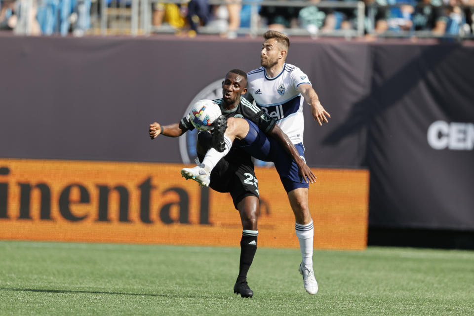 Charlotte FC defender Harrison Afful, left, and Vancouver Whitecaps defender Marcus Godinho battle for the ball in the first half of an MLS soccer match in Charlotte, N.C., Sunday, May 22, 2022. (AP Photo/Nell Redmond)